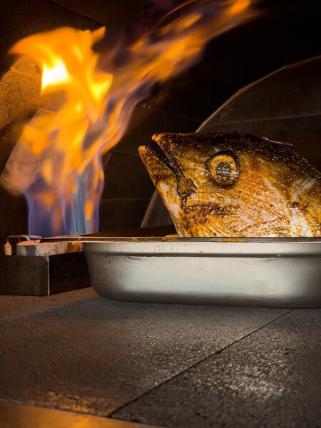 Whole fish cooking over an open flame at a beachfront restaurant in Kuta Lombok